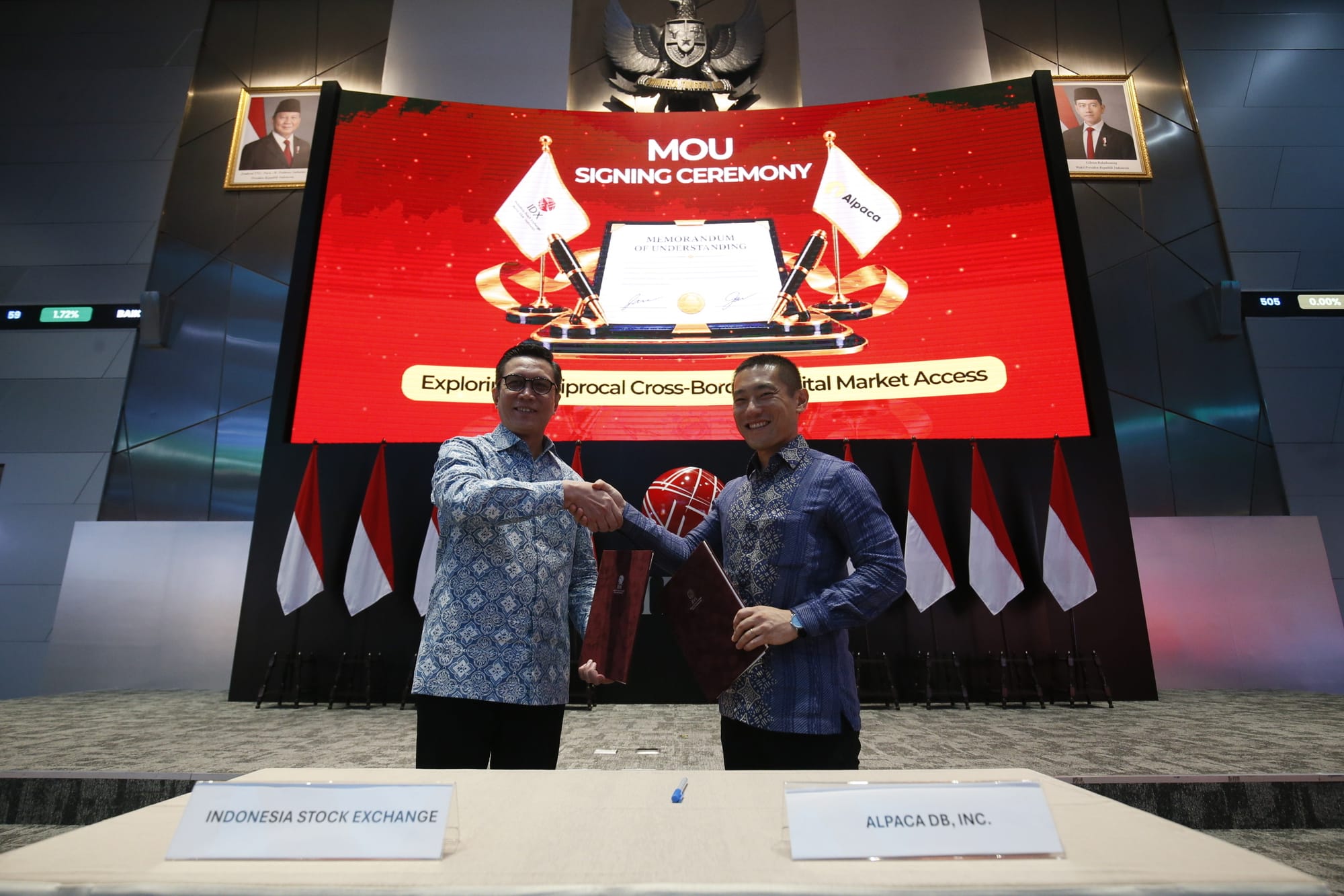Jeffrey Hendrick, President Director of Indonesia Stock Exchange, and Yoshi Yokokawa, Co-Founder and CEO of Alpaca, shake hands after signing the agreement.
